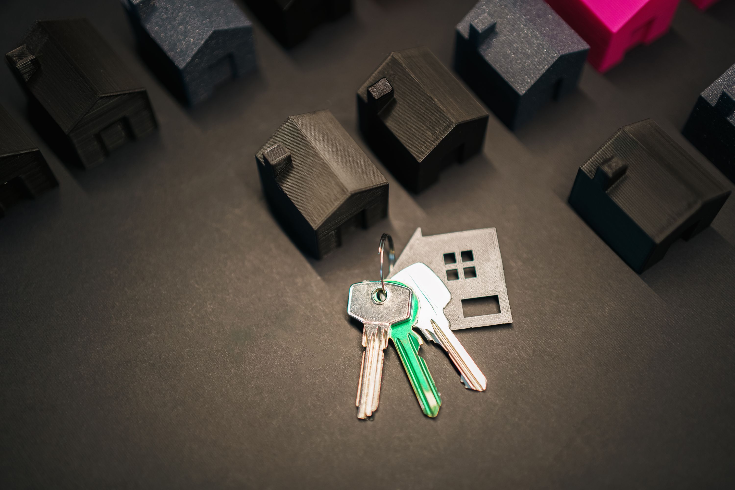 House keys beside miniature house models on a tabletop.