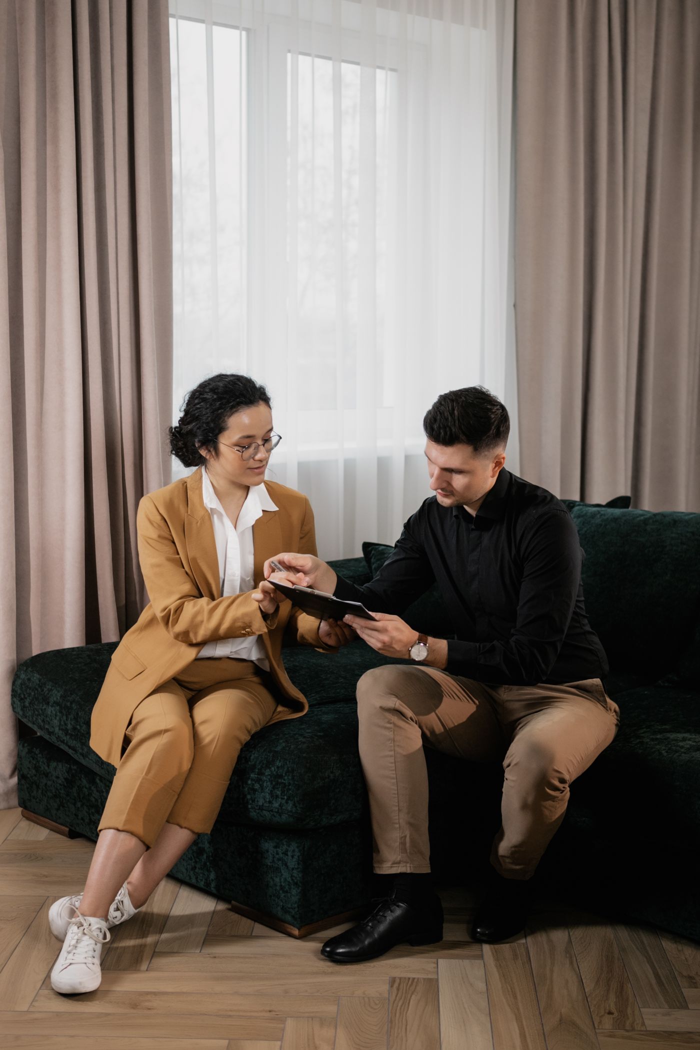 Two people discussing documents while seated on a sofa.